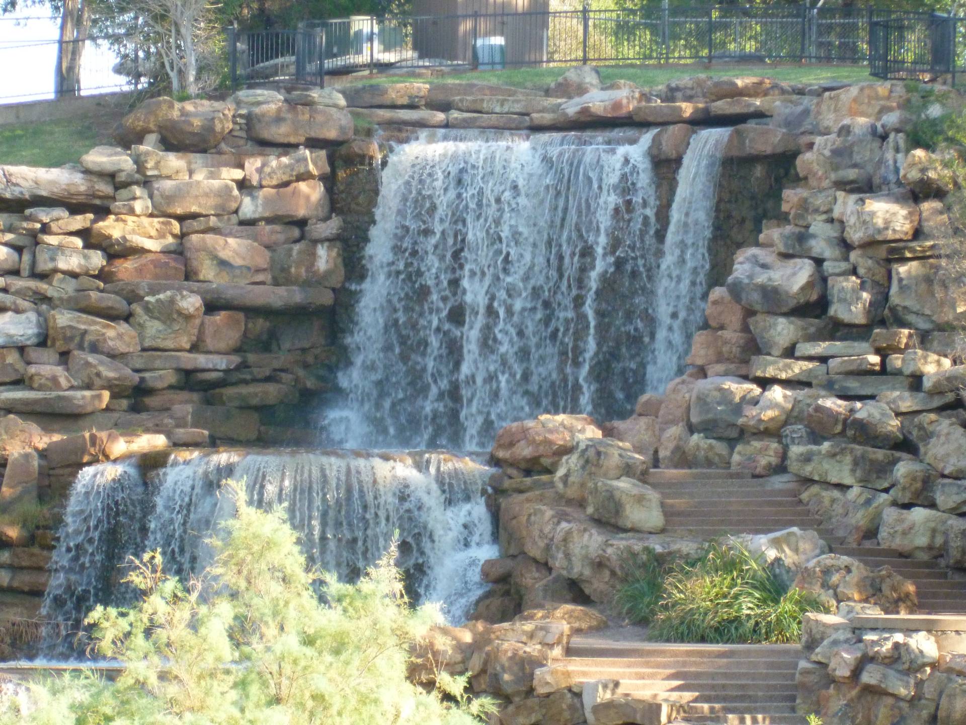 A mesmerizing image showcasing the striking cascades of the Wichita Falls, with water rushing over rugged rocks and framed by native Texan flora, illustrating Wichita Falls' unique connection to its natural landmarks.